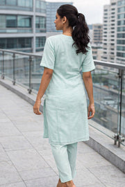 Woman in a light blue chikankari embroidered kurta outfit standing on a rooftop with cityscape background.  This picture is showing the back look of the kurta - 10076188